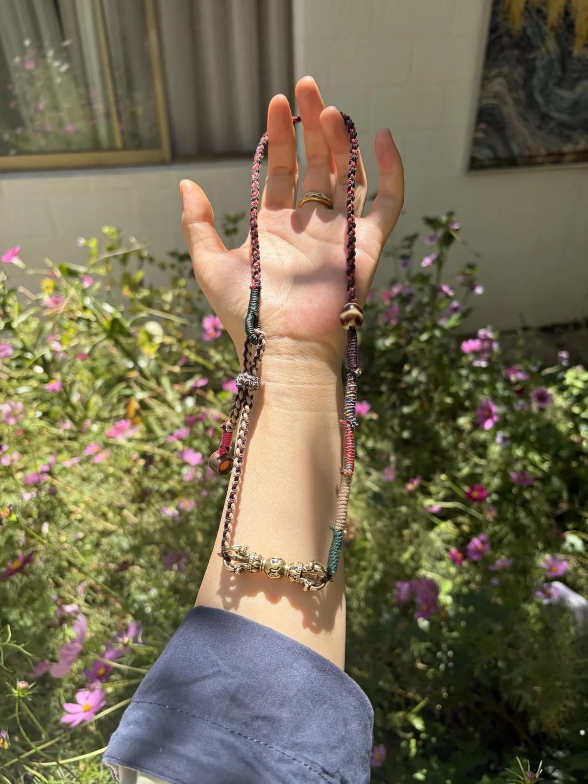 A handmade bracelet worn on a raised wrist in sunlight