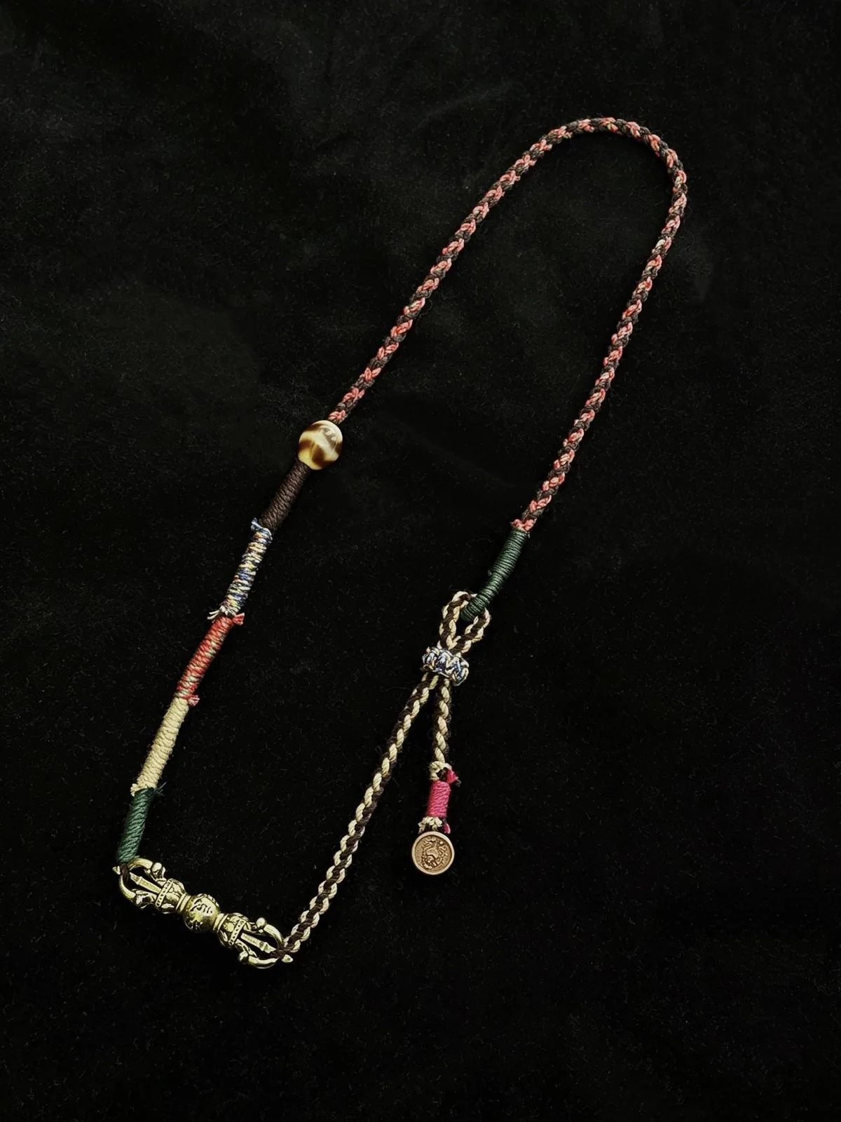 A handmade cord necklace arranged on black cloth
