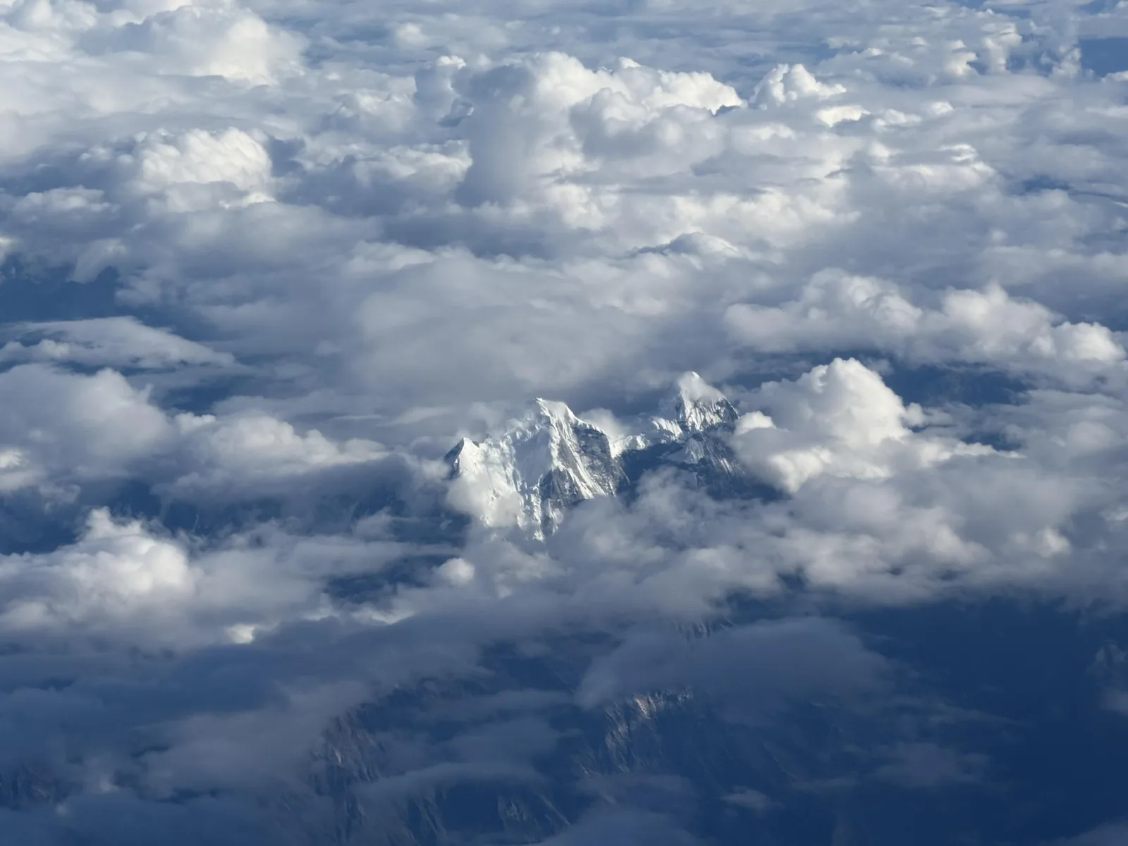 Snow-covered Himalayan peaks rising through layers of cloud