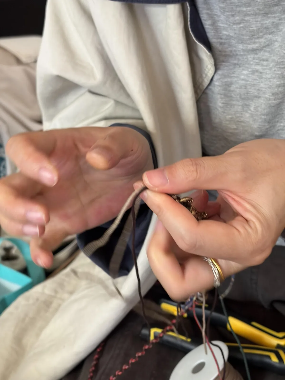 Close view of fingers threading a small jewelry component onto cord
