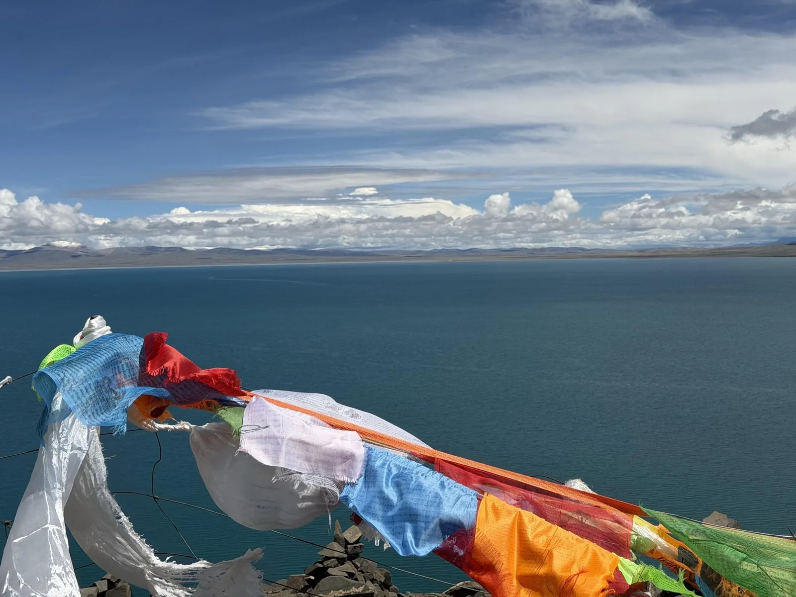 Prayer flags moving above the deep blue water of Namtso Lake