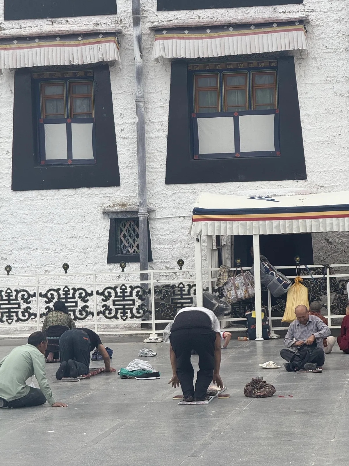 Pilgrims bowing in a monastery courtyard beneath dark framed windows
