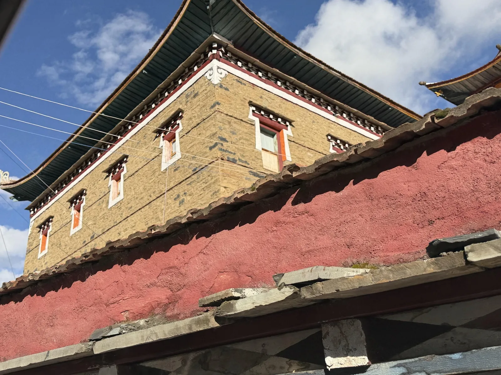 A weathered red and ochre wall at Samding Monastery under a blue sky