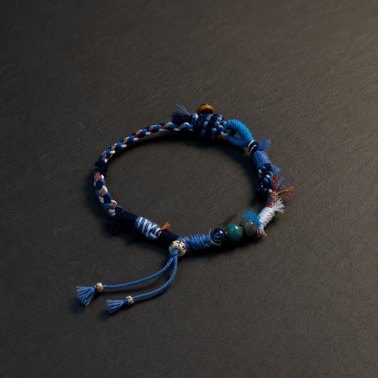 LHARI Blue Wind Prayer Cord Bracelet black background 45-degree view