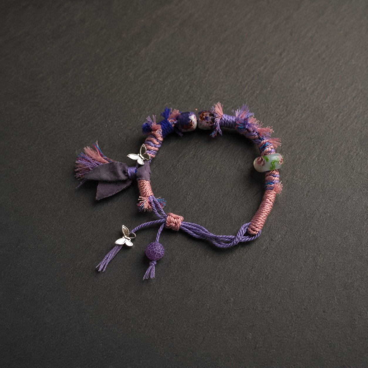 LHARI Lilac Butterfly Prayer Cord Bracelet black background 45-degree view